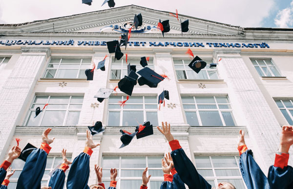 [Photo of college graduates throwing their caps into the air. Photo Credit to Unsplash]