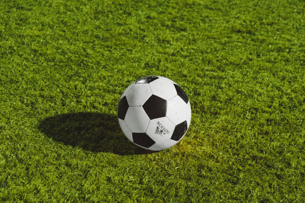 [A Football Lying on the Field. Photo Credit to Unsplash]